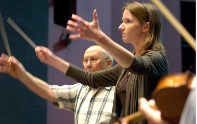 a professor and student wave batons to conduct a university orchestra