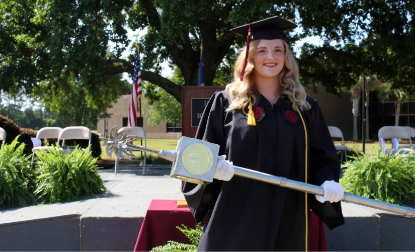 Graduate holds the Palmetto College mace during commencement