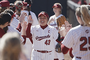 graphic that has a frame with the words Inside Carolina over an image of a softball player high-fiving her teammates