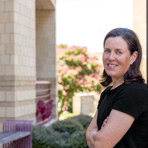 woman stands outside leaning against a building