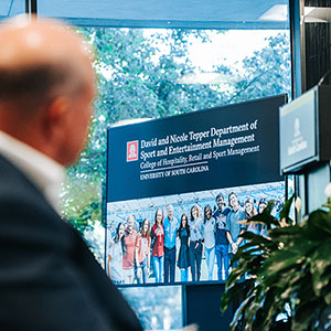 Carolina Panthers owner David Tepper looking toward video screen displaying logo and photo of students