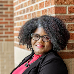 woman stands outside with a brick wall in the background