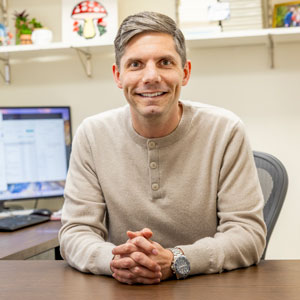 Colin Evans smiles at his desk.