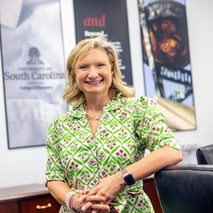 Betsy Blake, pharmacy professor, smiles for a photo in an academic building.